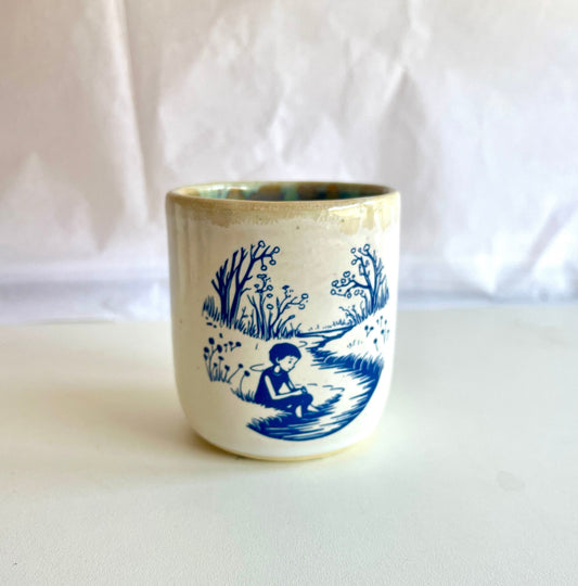 Ceramic cup with blue scenic design on a white background