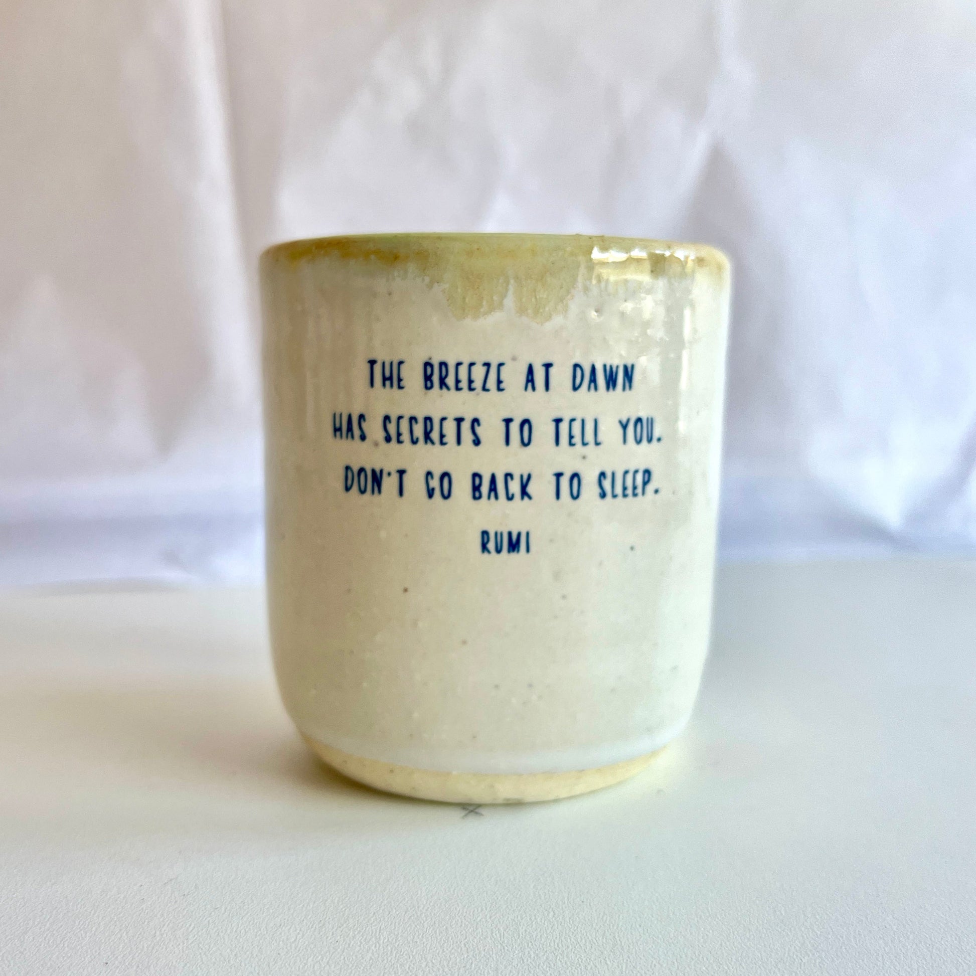 Ceramic mug with a quote by Rumi on a white background